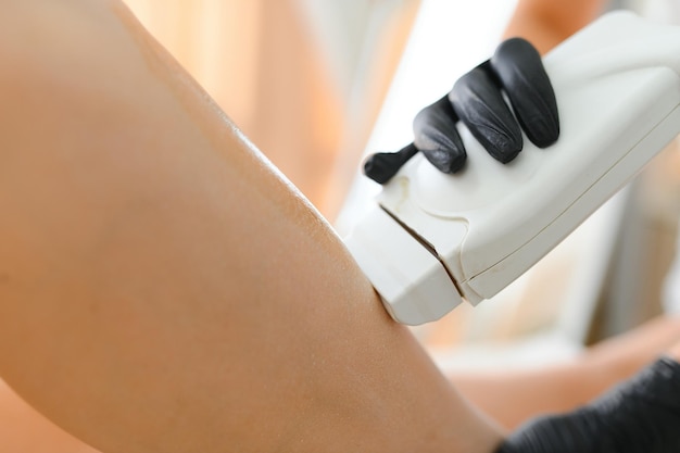 Esteticista depilando pernas femininas em centro de spa
