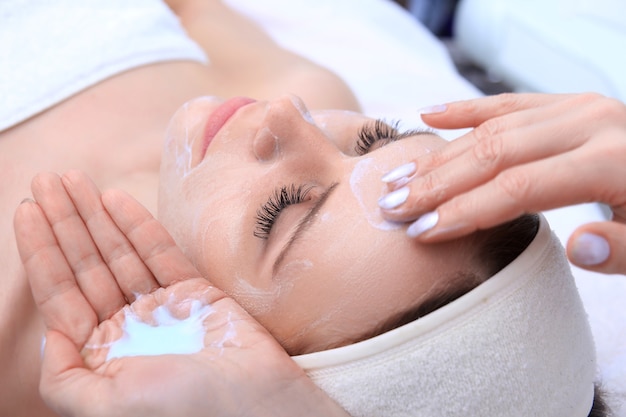 Esteticista faz limpeza e esfoliante facial para linda garota. Salão de beleza.