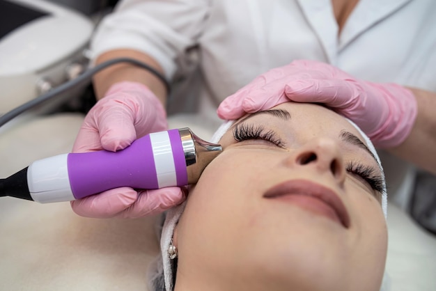 Esteticista fazendo procedimento de limpeza com ferramenta de hardware no rosto feminino no spa