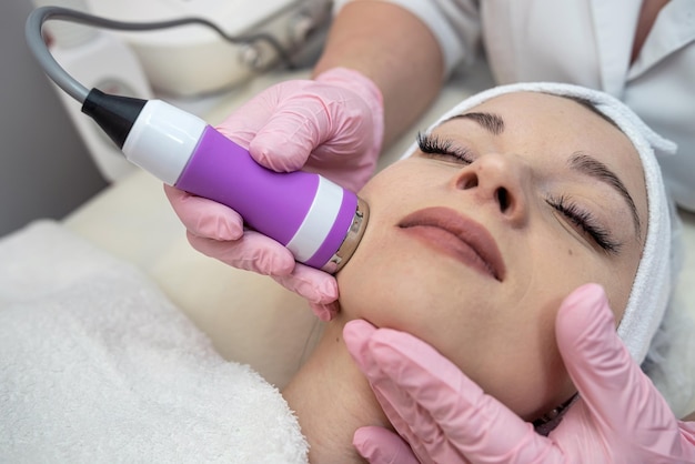 Esteticista fazendo procedimento de limpeza com ferramenta de hardware no rosto feminino no spa