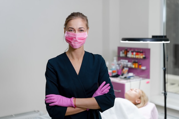 Esteticista fica em máscara médica rosa e sorrisos.