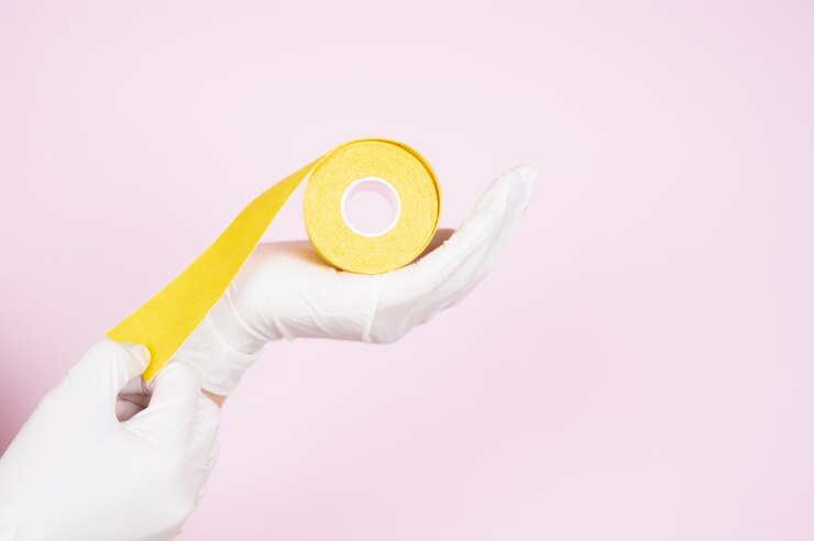 Foto la esteticista con guantes protectores sostiene cintas de kinesio en sus manos sobre fondo rosa. procedimientos anti-envejecimiento.