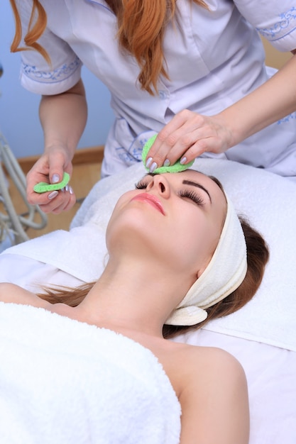 Esteticista hace facial de limpieza y exfoliación para una chica hermosa. Salón de belleza.