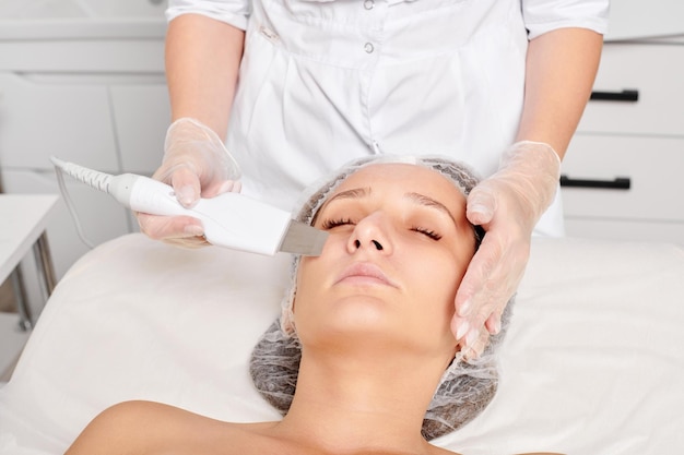 Esteticista hace peeling ultrasónico facial para rejuvenecer el cuidado de la piel de la cara de la mujer en el salón de belleza spa