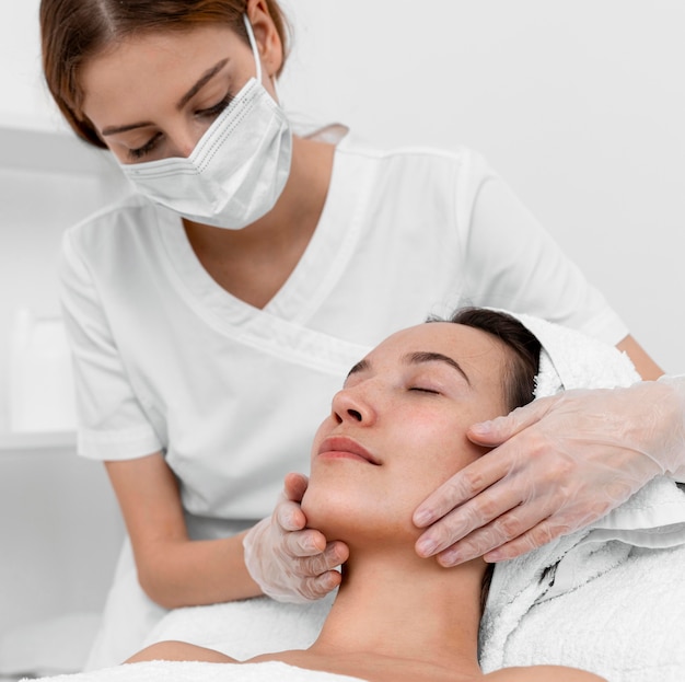 Foto esteticista haciendo rutina de belleza facial para clienta