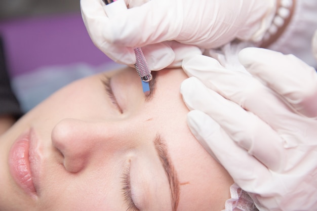 Esteticista haciendo tatuajes de cejas para mujer