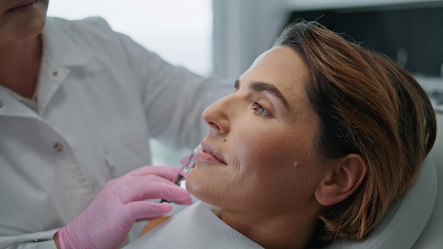 Esteticista injetando rosto de mulher na clínica de cosmetologia para levantamento de perto