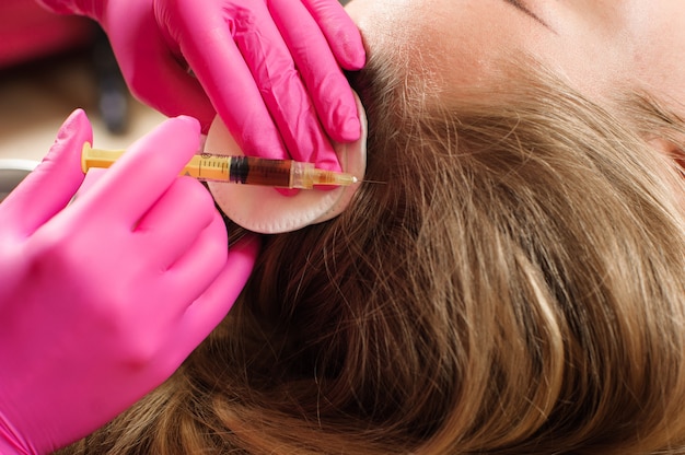 Esteticista inyectando colágeno en la cabeza de la mujer