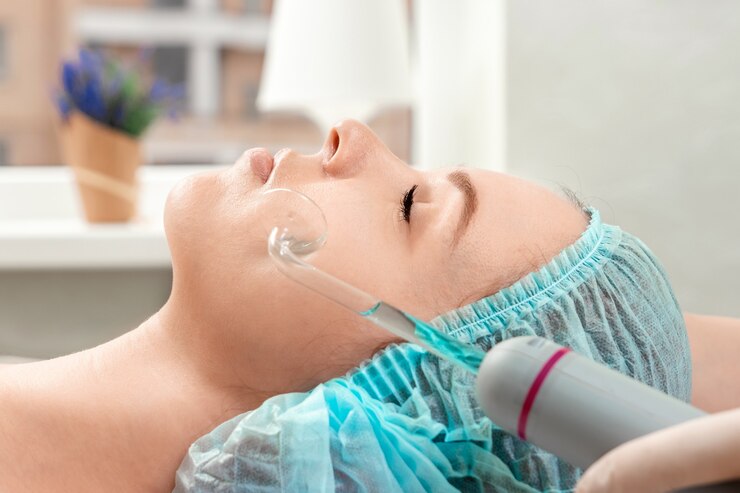 Foto la esteticista limpia la piel del aparato de cosmetología darsonval de las niñas.