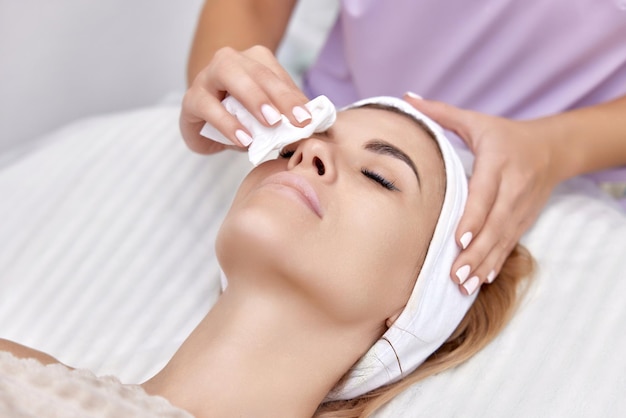 esteticista limpia la piel de una mujer hermosa con una esponja