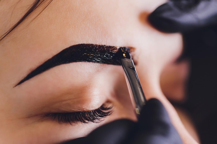 Foto esteticista maquiadora aplica tinta henna em sobrancelhas previamente arrancadas design aparadas em um salão de beleza na sessão de correção cuidado profissional para o rosto