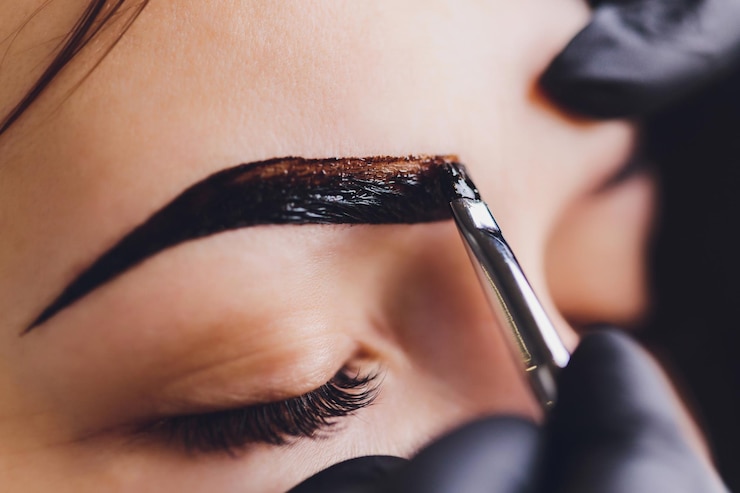 Foto esteticista maquiadora aplica tinta henna em sobrancelhas previamente arrancadas design aparadas em um salão de beleza na sessão de correção cuidado profissional para o rosto