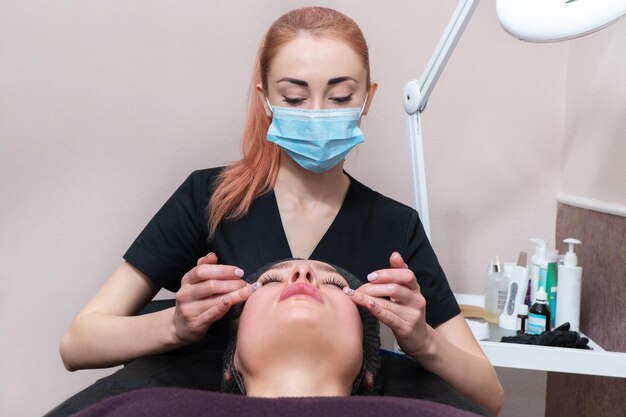 esteticista masajea la cara del paciente en el área de los ojos