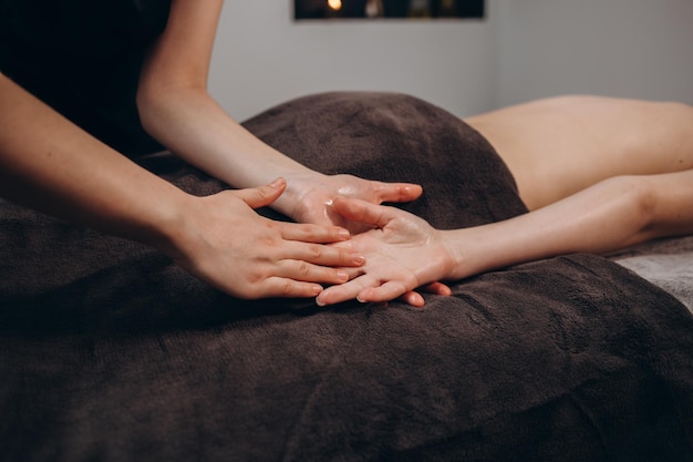 Esteticista masajeando la mano del cliente del salón de spa femenino