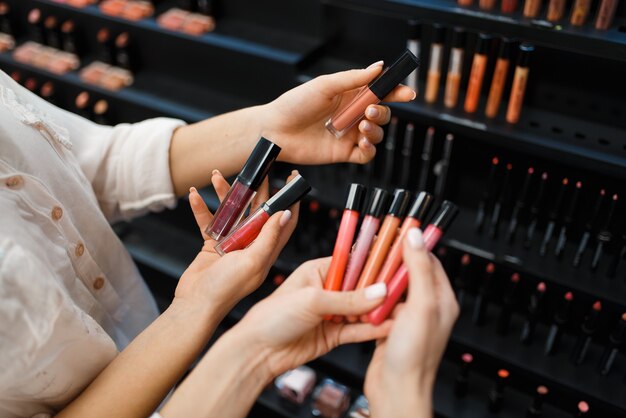 Esteticista y mujer tiene esmalte de uñas en el escaparate de la tienda de cosméticos. Salón de belleza de lujo, clienta y esteticista en el mercado de la moda