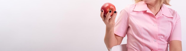 Esteticista de pancartas con uniforme rosa sosteniendo una gran manzana roja Inyecciones de Botox Copiar espacio