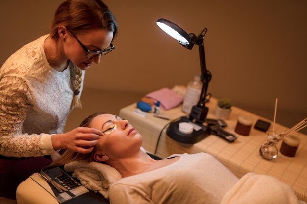 Esteticista peinando pestañas extendidas para modelar en el salón de belleza.