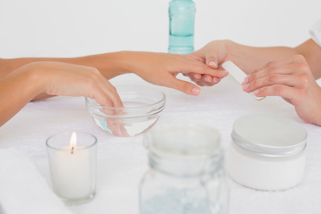 Esteticista presentación de uñas del cliente femenino en el salón de belleza del spa