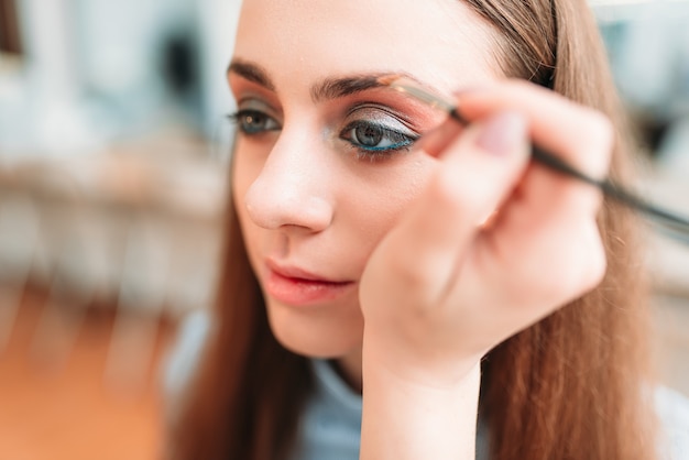 Esteticista profesional trabaja con cejas de mujer en estudio de belleza.