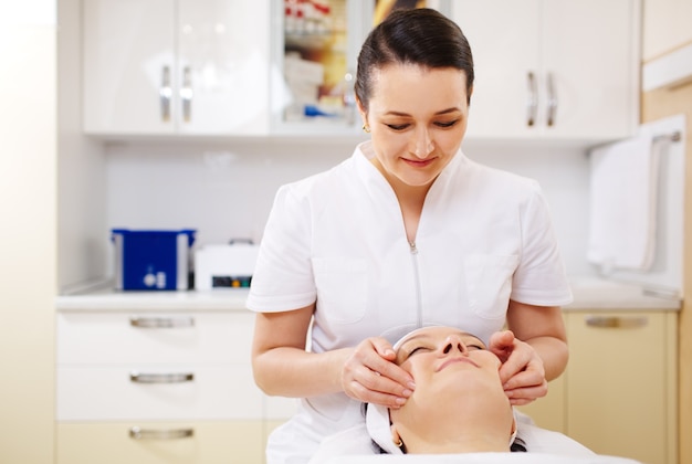 Foto esteticista profissional durante a sessão de massagem facial