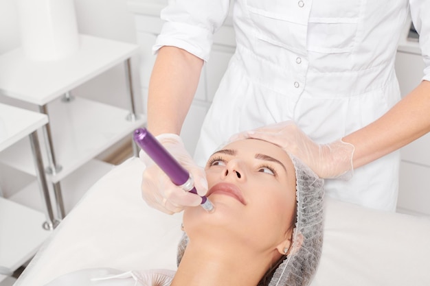 Esteticista realiza una inyección de mesoterapia para el procedimiento de rejuvenecimiento de la cara de la mujer en un salón de belleza