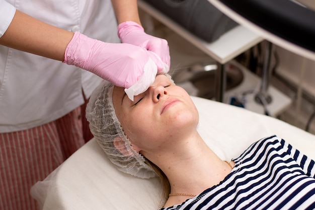 Foto esteticista realiza procedimientos en el rostro de la mujer.