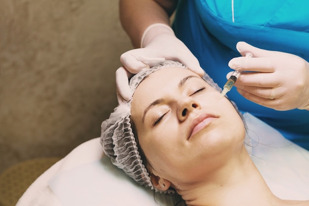 Esteticista realiza tratamento de mesoterapia com agulha no rosto de uma mulher