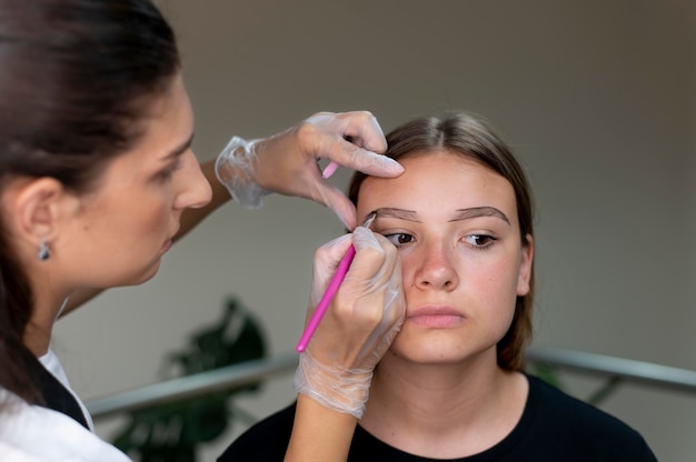 Esteticista realizando procedimento de microblading em uma jovem