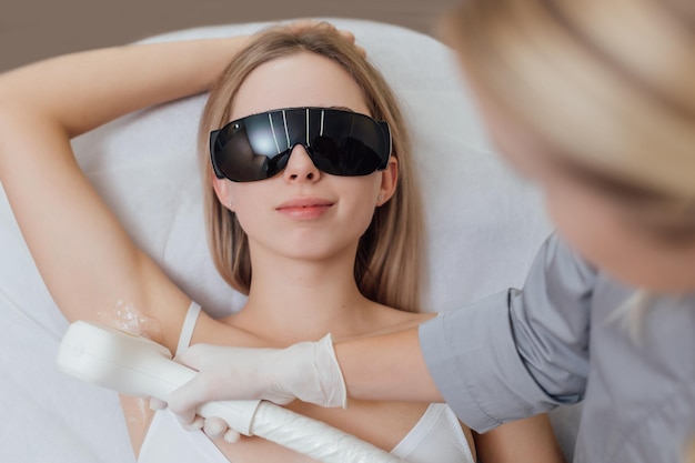 Esteticista remove pêlos em lindas pernas femininas usando um procedimento de depilação a laser em beleza