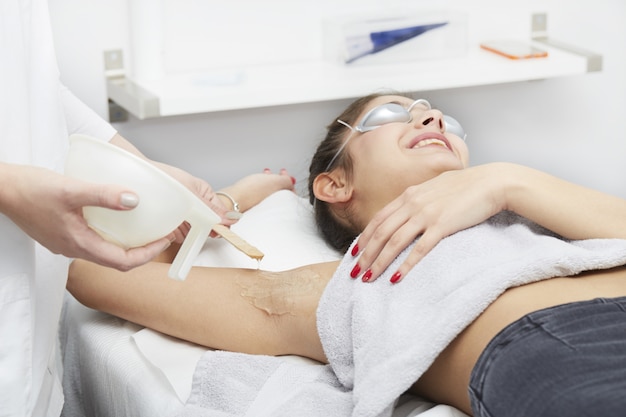 Foto esteticista, removendo o cabelo da jovem mulher com laser