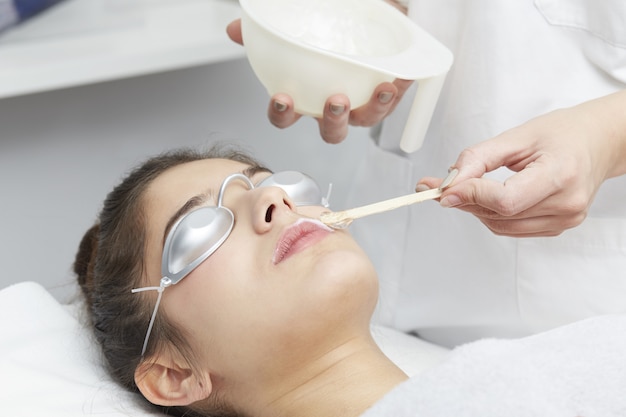 Esteticista, removendo o cabelo da jovem mulher com laser