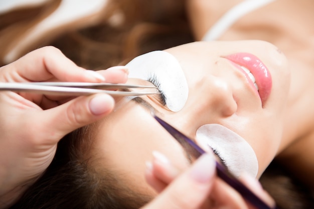 Esteticista trabajando en la mejora de las pestañas de seda en un estudio de belleza.