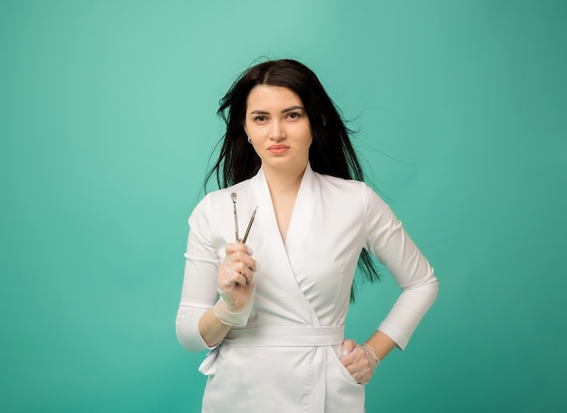 Una esteticista con un uniforme blanco sostiene herramientas de limpieza facial en azul