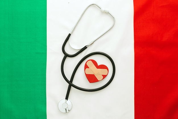 Un estetoscopio cerca de un corazón sobre una bandera italiana