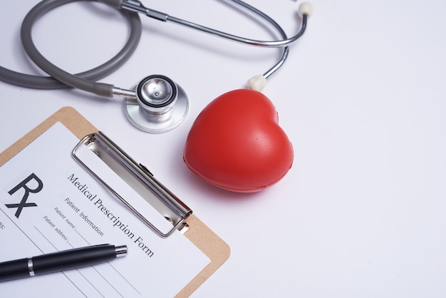 Estetoscopio con corazón. Estetoscopio y corazón rojo sobre mesa de madera. Concepto de seguro de vida hospitalario. Idea del día mundial de la salud del corazón. Concepto de medicina o farmacia. Formulario médico vacío listo para ser utilizado.