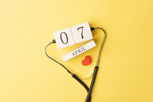 Estetoscopio corazón rojo y calendario del 7 de abril sobre fondo amarillo Mundo de seguros de vida de salud