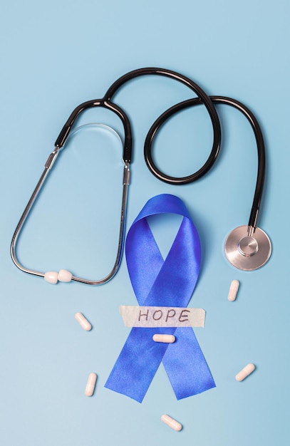 Estetoscópio de fita azul e pílulas sobre um fundo azul