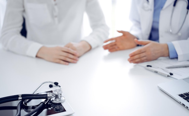 Estetoscópio deitado no tablet na frente de um médico e paciente sentados perto um do outro no fundo. Medicina, conceito de saúde.