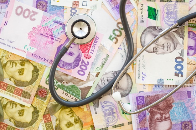 Estetoscopio y dinero El concepto de medicina costosa Grivna ucraniana Muchos billetes