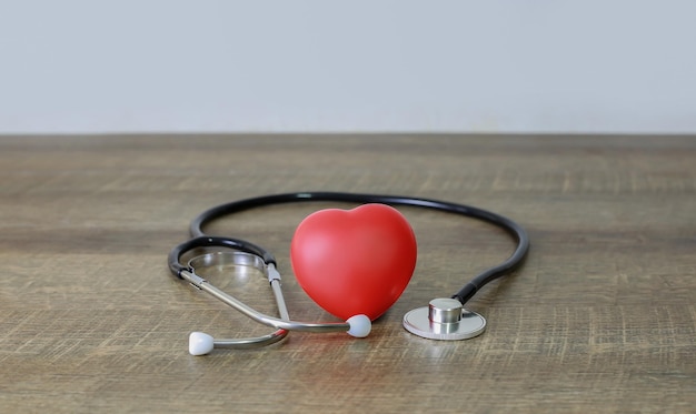 Estetoscópio e exame de coração vermelhos no antigo conceito de cuidados de saúde de piso de madeira