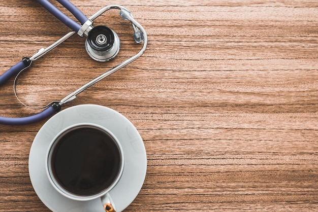 Estetoscópio e xícara de café na mesa de madeira