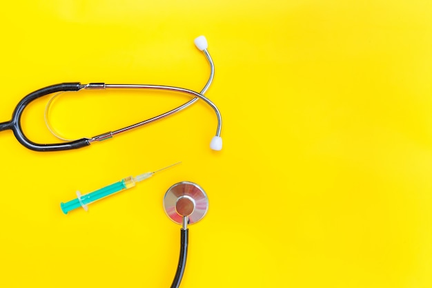 Foto estetoscopio de equipo de medicina y jeringa aislado sobre fondo amarillo