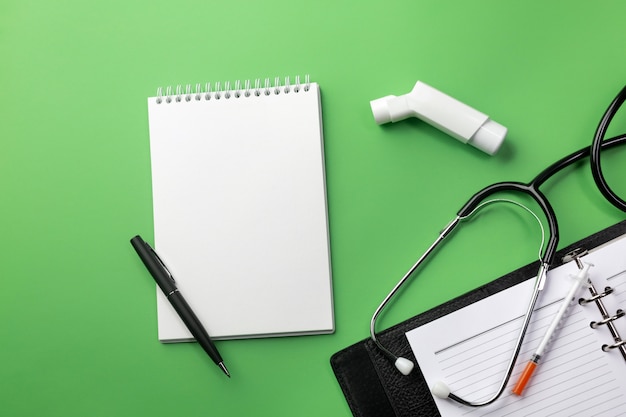 Foto estetoscopio en escritorio de doctores con cuaderno e inhalador