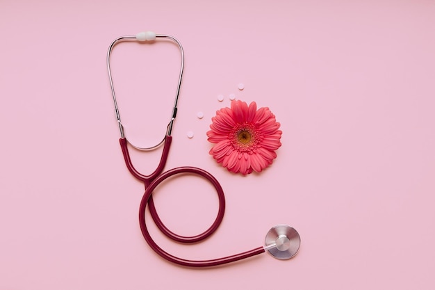 Estetoscopio con flor sobre un fondo rosa Concepto de salud de la mujer