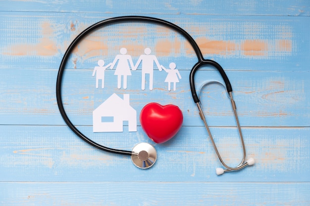 Foto estetoscopio con forma de corazón rojo, papel de la familia y la casa en azul pastel