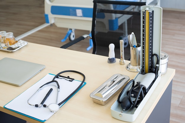 Foto estetoscópio, laptop e outro objeto médico na mesa do médico.