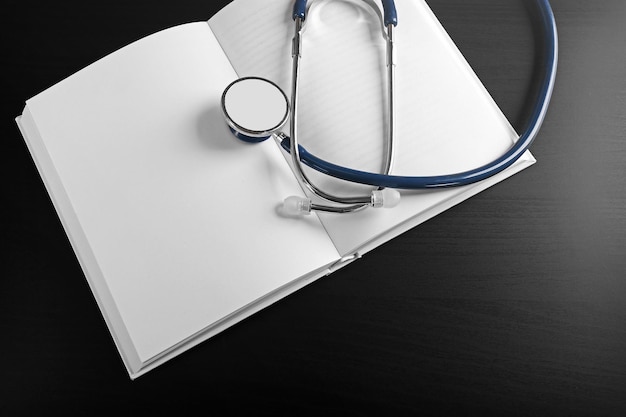 Estetoscopio con libro abierto sobre fondo de madera Concepto de literatura médica