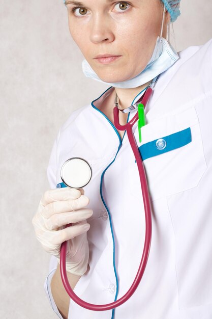 Un estetoscopio en la mano de un médico vestido con un uniforme profesional blanco