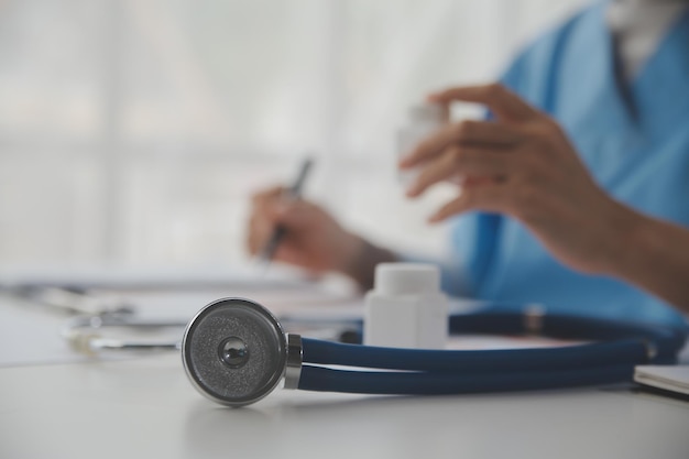 Estetoscopio y médico de antecedentes usando una computadora portátil en el escritorio de la clínica trabajando en una computadora en la oficina de la habitación