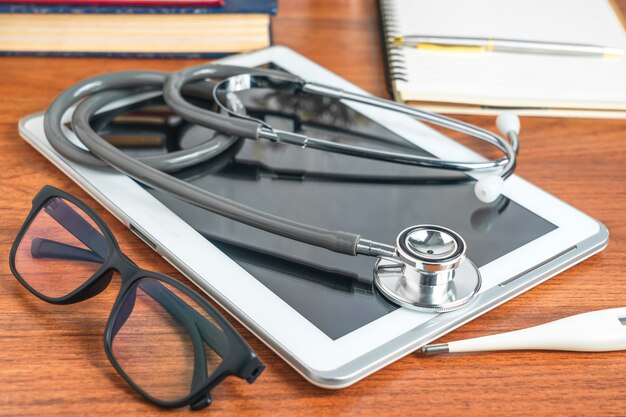 Foto estetoscopio médico para chequeo médico con tableta en la mesa del médico como concepto médico